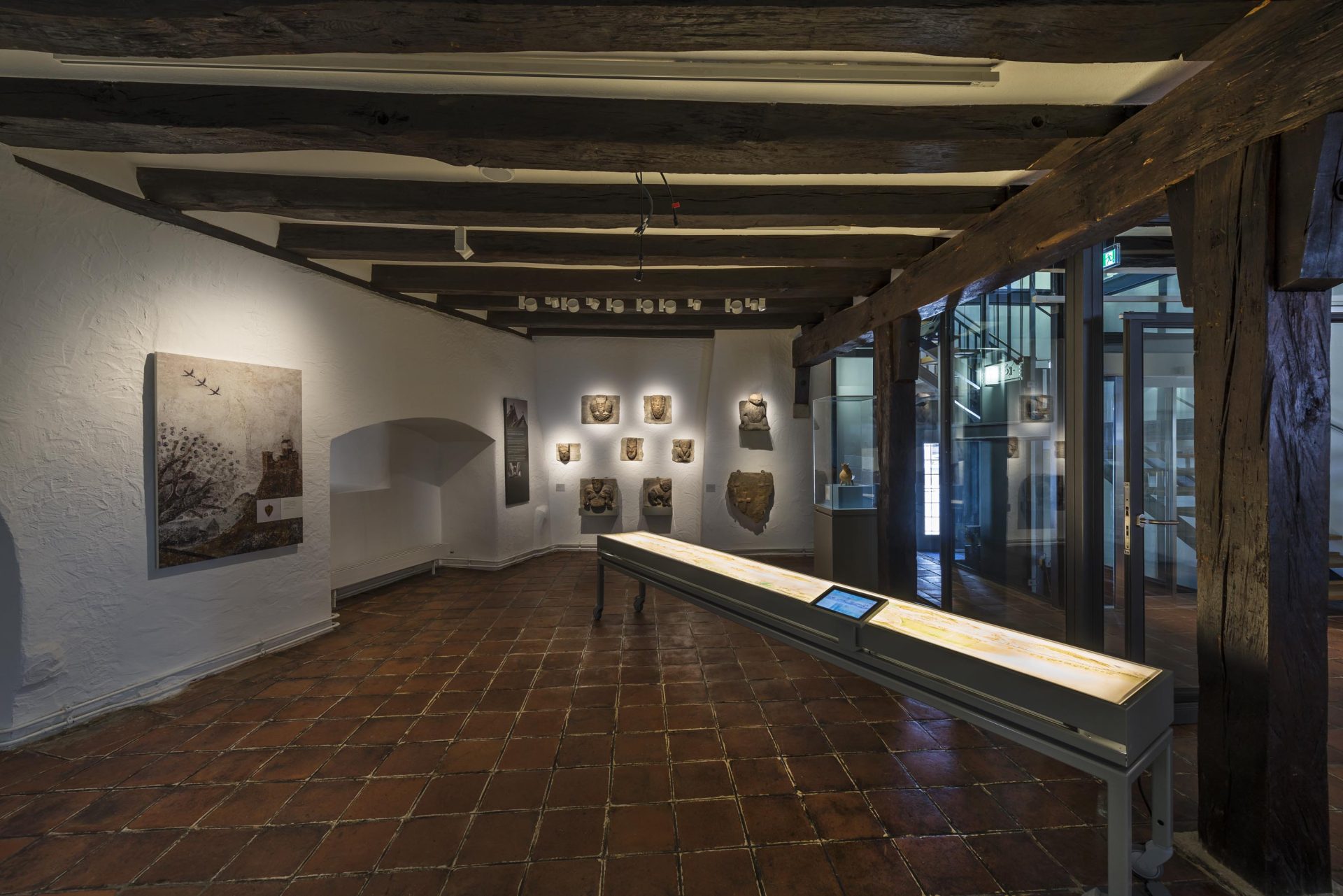 Ein Museum mit Bilderwänden und einem langen Informationsdisplay im Innenraum.